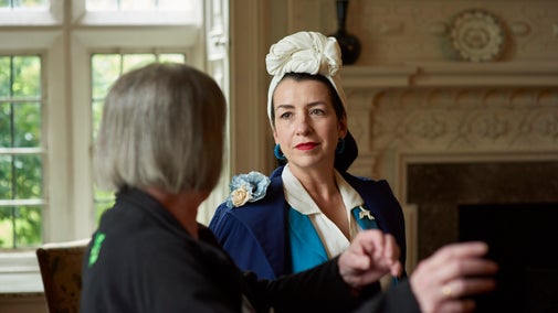 Visitor listens keenly to volunteer explaining in a historic room
